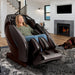 Kyota Hatsumei M900AI 4D Massage Chair in Brown with woman relaxing inside the house.